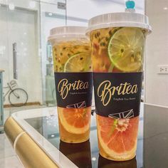 two drinks are sitting on a counter in front of a glass case with the name brittea