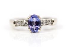 a tan and white gold ring with an oval cut tanzanite surrounded by diamonds