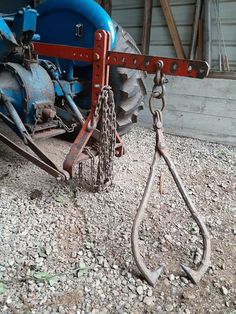 a blue and red tractor with chains attached to it's front end on gravel