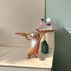 a cat figurine holding a tray on it's back while standing on its hind legs