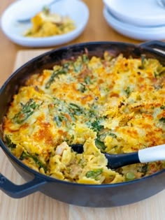 a casserole dish with broccoli, cheese and other toppings on a wooden table