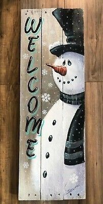 a wooden sign with a snowman painted on it