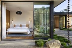 a bedroom with glass doors leading to the outside patio and bed in the foreground