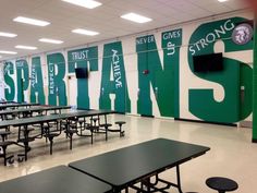 an empty cafeteria with green tables and black benches in front of a sign that says spartan