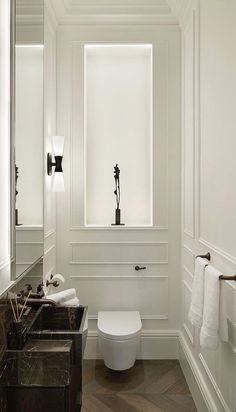 a white toilet sitting next to a sink in a bathroom under a window with two towels hanging on the wall