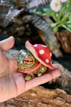 a small frog figurine sitting on top of a person's hand