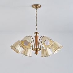 a chandelier hanging from the ceiling with three shades of light on top of it