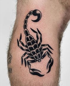 a black and white scorpion tattoo on the back of a man's leg,