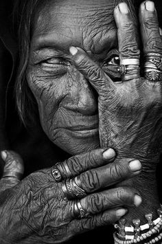 an old woman holding her hands to her face with rings on her fingers and the other hand in front of her face