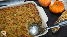 a casserole dish with corn on the cob and pumpkins in the background