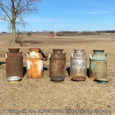 an assortment of old, rusty canisters sitting in the middle of a field