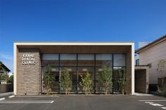 an empty parking lot in front of a building with large windows and plants on the outside