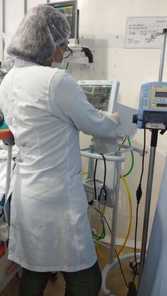 a woman in white lab coat operating machine