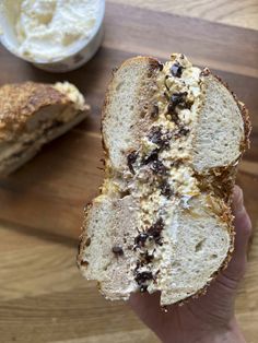 a person holding a piece of bread with cream cheese and chocolate toppings on it