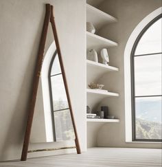 an arched window in a white room next to a shelf with vases on it