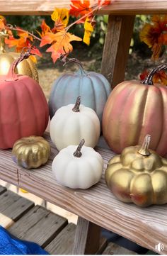 painted pumpkins are sitting on a wooden bench