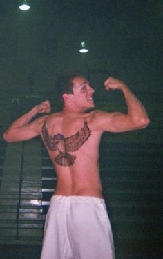 a shirtless man with an eagle tattoo on his chest flexing it's muscles