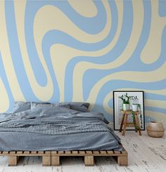 a bed sitting on top of a wooden pallet in front of a blue and white wall