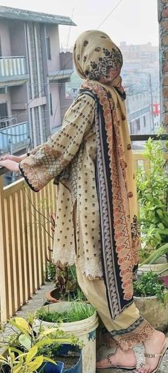 a woman standing on top of a balcony next to potted plants