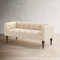 a white couch sitting on top of a hard wood floor next to a gray wall