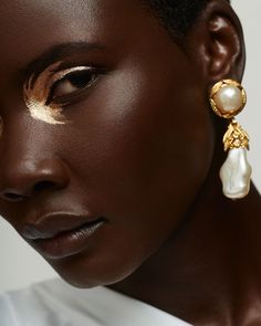 a woman wearing gold and pearl earrings