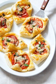 small appetizers with tomatoes and cheese on a white plate next to a knife