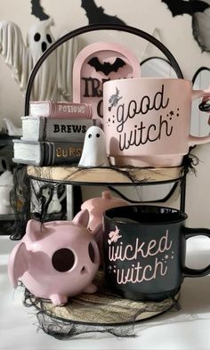 two black and pink coffee mugs sitting on top of a shelf with halloween decorations