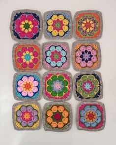 nine crocheted squares are arranged in the shape of flowers on a white surface