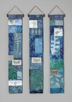 two wall hangings made out of fabric with leaves and other things on the sides