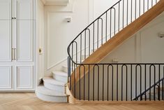 an empty room with white walls and wooden flooring next to a spiral stair case