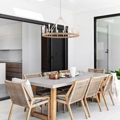 a dining room table with chairs and a chandelier hanging from it's ceiling