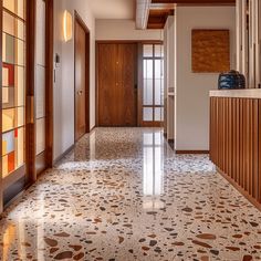 A mid-century modern hallway with terrazzo flooring in a unique, speckled pattern, complemented by warm, rich hardwood accents and geometric tiles adding visual interest3 Mid Century Modern Hallway, Mid Century Hallway, Mid Century Entryway, Mid Century Tile, Modern Remodel, Mid Century Interior, Mcm House, Hallway Designs, Modern Hallway