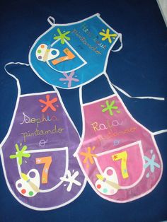 three children's bibs with numbers and designs on them, one for each child