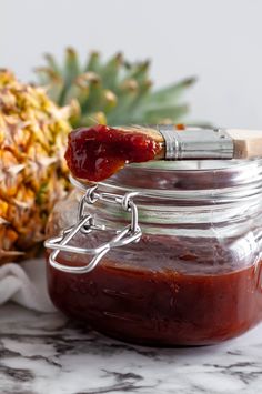 a pineapple sitting next to a jar filled with jam