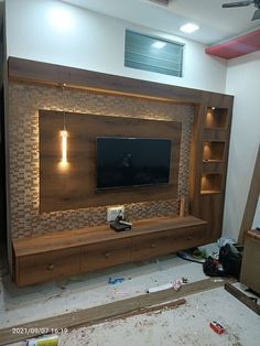 a living room with a large television mounted on the wall and wooden shelves in front of it