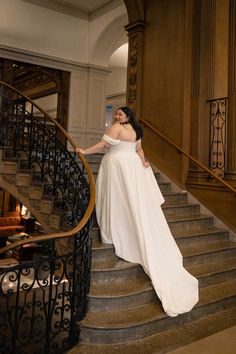 a woman in a white dress is standing on some stairs