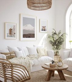 a living room filled with white furniture and pictures hanging on the wall above it's coffee table