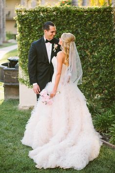 a bride and groom standing in front of a hedge