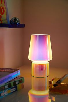 a colorful lamp sitting on top of a table next to some books and a pair of scissors