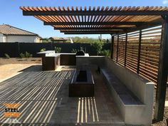 an outdoor kitchen area with grills, benches and pergolated roofing in the background