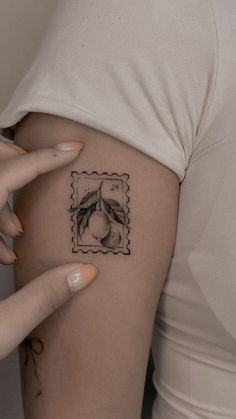 a woman's arm with a postage stamp tattoo on the left side of her thigh