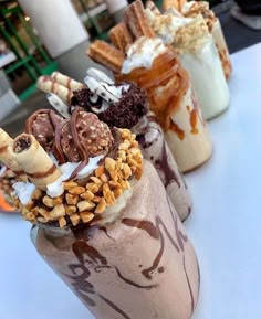 three glasses filled with different types of desserts on top of a white table next to each other