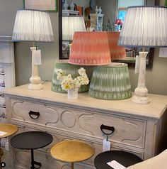 three lamps are sitting on top of a dresser with stools in front of it