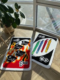 two rugs with different designs on them sitting next to a potted plant in front of a window