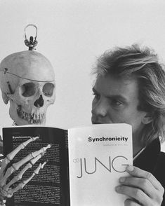 a man reading a book next to a human skull