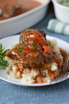 a white plate topped with mashed potatoes covered in gravy and meat sauce