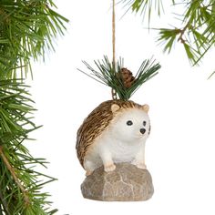 an ornament shaped like a hedgehog sitting on a rock under a pine tree