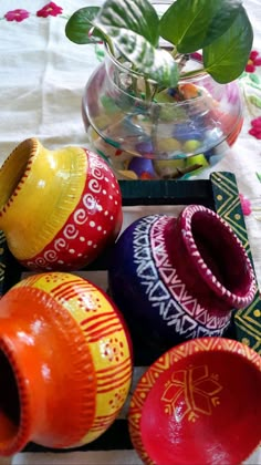 several colorful vases sitting on top of a table next to a potted plant