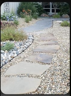 a stone path in front of a house with gravel and rocks on the ground next to it