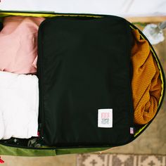 an open suitcase filled with clothes on top of a rug